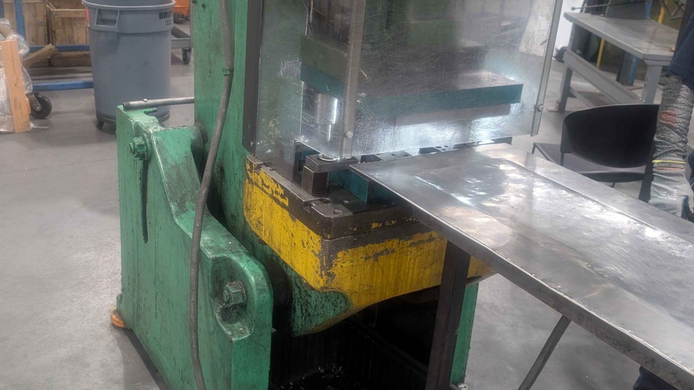 Gap-frame mechanical punch press with a clear point-of-operation guard over the die area and sheet stock running across the outboard support table