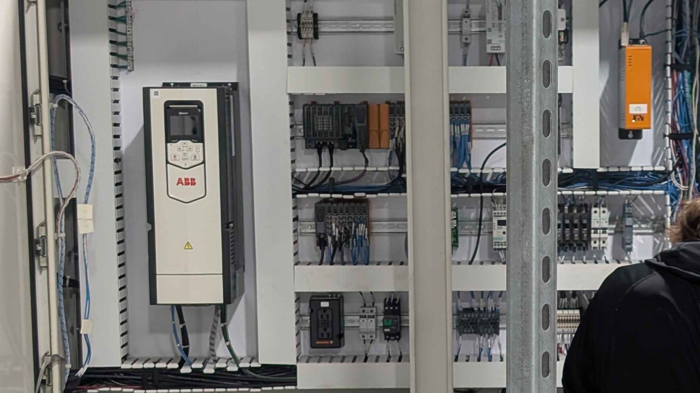 ABB variable frequency drive mounted in a control cabinet alongside DIN rail I/O modules, contactors and terminal blocks